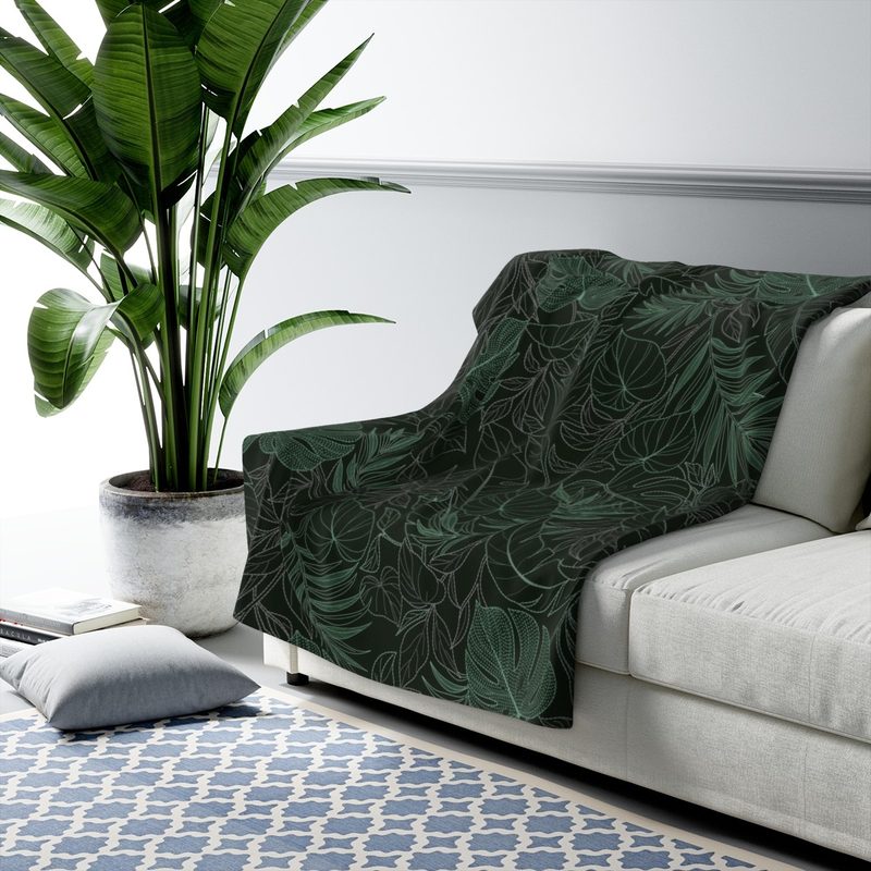 Jungle blanket draped over a pale grey sofa next to a large potted plant