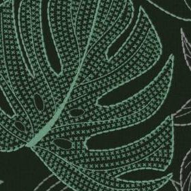Close-up of the finished pattern, a monstera leaf filled with rows of small green crosses inside a stitched outline